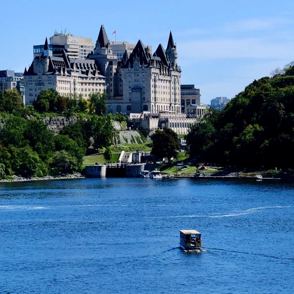 View of Ottawa river with a boat in the foreground and Chateau Laurier in the background